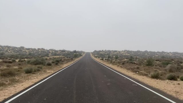 Jaisalmer, Rajasthan, India - 12 January 2024: Wide view of desert road through the Rajasthan. Beautiful view of desert with clear blue sky from road trip in JAISALMER.