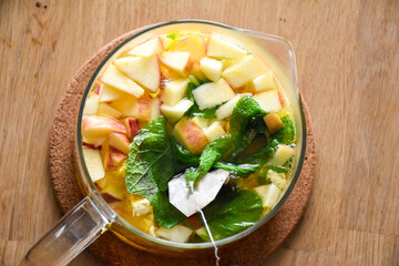 Glass hot teapot with sliced apple, orange, mint and cinnamon