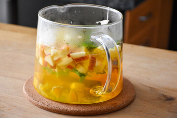 Glass hot teapot with sliced apple, orange, mint and cinnamon