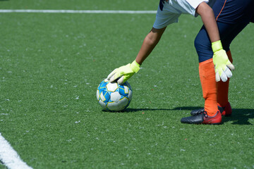 Girl goalkeeper placing the soccer ball to kick it far in the football field