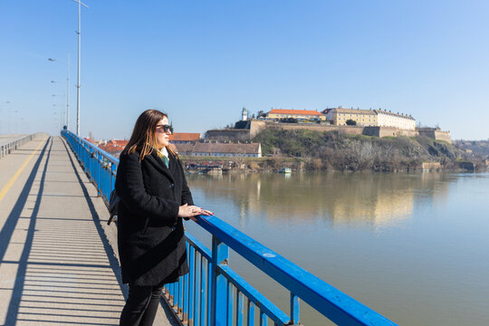 Woman enjoying a beautiful view of Petrovaradin Fortress at the bridge over the Danube river, Novi Sad, Serbia.