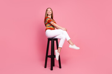 Full size portrait of cheerful creative girl sit chair look empty space imagine isolated on pink...