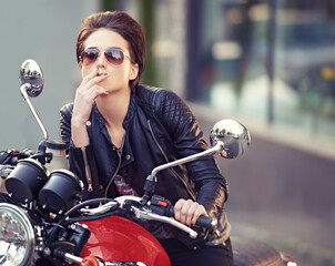Fototapeta na wymiar Motorcycle, leather and biker in city with cigarette for travel, or road trip as rebel. Fashion, street and woman smoker with attitude on classic or vintage bike for transportation or journey
