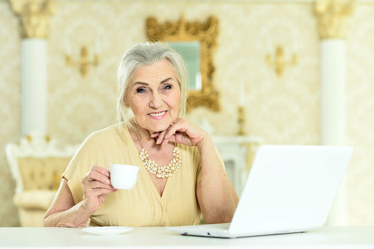 Portrait of senior woman sitting at table with laptop