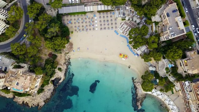 Playa illetas with clear waters and beachgoers in mallorca, spain, during summer, aerial view