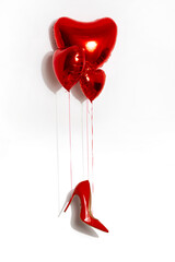 Sexy red high-heeled shoe hangs on red heart-shaped balloons. Valentine's day.