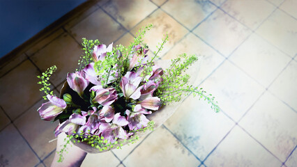Alstroemeria flowers against tiled floor. Vintage style flower bouwuet color purple white green....