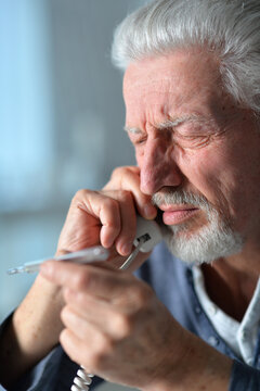 Portrait of sad sick senior man calling doctor