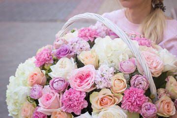 Girl florist holding a basket of flowers in her hands