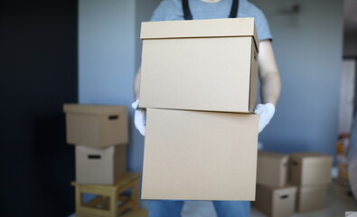 Close-up of male carrying cardboard boxes in gloves. Delivery service. Unpacked personal things in...