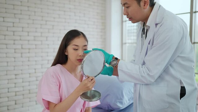 Young Asian male surgeon explaining the nose surgery procedure to woman patient before undergoing surgery in surgery clinic. Consulting for nose surgery, cosmetologist concept