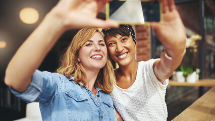 Smiling diverse attractive girlfriends taking a selfie outside