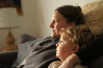 Mother and son portrait in a residential house with contrast light from outside. Side view.