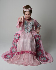 Fun length portrait of female model wearing an opulent pink gown, costume of a historical French...