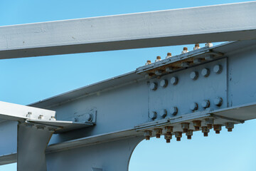 Parts of a modern metal bridge in close-up against a blue sky background. Metal structures...