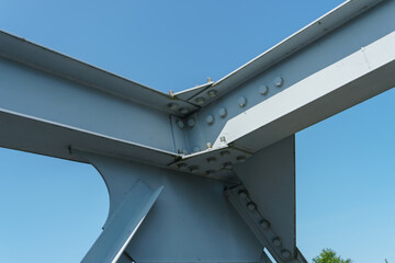 Parts of a modern metal bridge in close-up against a blue sky background. Metal structures...