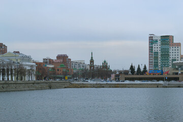 A city landscape with a river and various buildings on a cloudy day