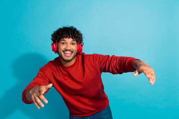 Portrait of overjoyed nice young man have good mood listen favorite song dancing isolated on blue color background