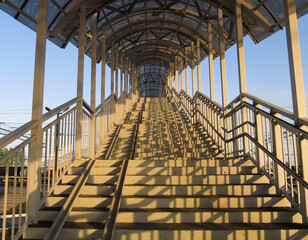 View from below on the stairs of the pedestrian bridge in the light of the sun at sunset