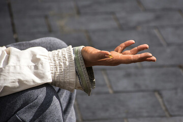 Detail of a man's arm and hand outstretched and asking for a donation.