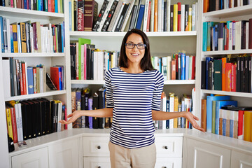 Woman, portrait and confidence by bookshelf in home with books for reading, learning or knowledge...