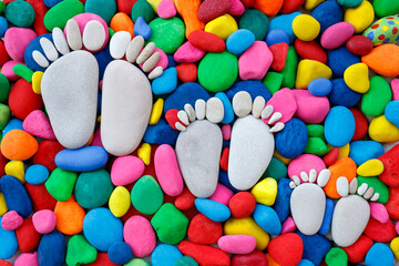 Family stone footprints on multi colored pebbles, top view