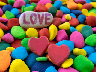 Two red hearts among multi colored pebbles  