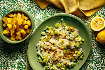 prato com peixe ao molho de alho-poró e maracujá acompanhado de batatas assadas sobre mesa