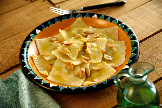 delicioso ravi&oacute;li recheado de ab&oacute;bora ao molho de manteiga e am&ecirc;ndoas sobre mesa de madeira r&uacute;stica
