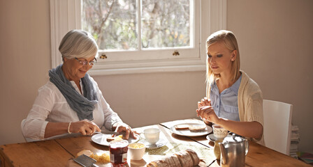 Happy woman, senior mother and eating breakfast, drinking tea and bonding at home together. Smile,...