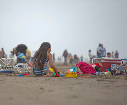 Ni&ntilde;a jugando en la playa haciendo castillos de arena