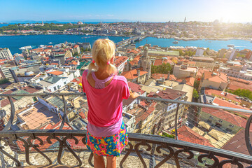 A lady observes a lively urban panorama on a sunlit day, taking in the breathtaking view from the Galata Tower in Istanbul, Turkey.