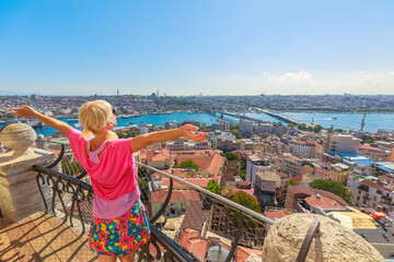 Back view of a woman with open arms enjoying the panoramic Istanbul cityscape from a high viewpoint on a sunny day of Istanbul in Turkey