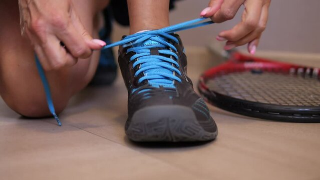 Observe preparation of woman as she carefully laces up her tennis shoes preparing for exciting tennis match This engaging footage provides intimate look into her dedication and focus on tennis court