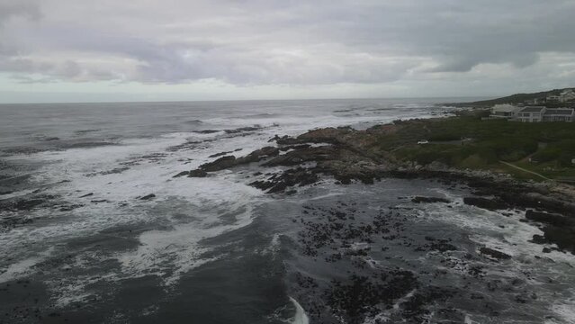 Hermanus Coast line fly over across wild waves and stone beach site with cloudy background