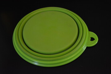 Green folding and multifunctional rubber plate, a bowl with a plastic edging on a black glossy surface.