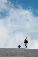Deux cyclistes arrivent en haut d'un col, photo minimaliste avec la route et le ciel