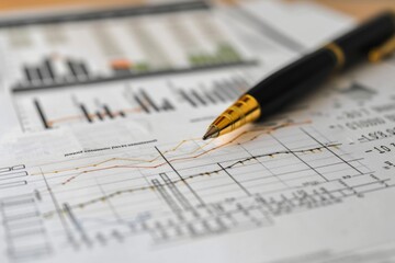 Close-up of a sophisticated financial analysis with a luxurious golden pen, highlighting the meticulous study of market trends on paper.