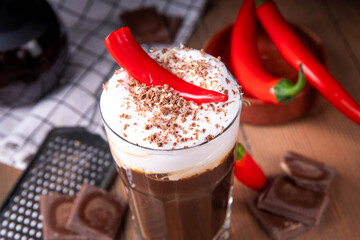 Hot spicy coffee latte with chili pepper, whipped cream and chocolate chips on top, copy space