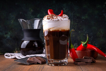 Hot spicy coffee latte with chili pepper, whipped cream and chocolate chips on top, copy space