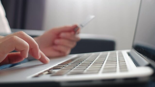 Close up of female hands of person entering credit card data laptop computer during pay for internet shopping online sitting alone on couch at home