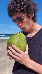 Fototapeta premium Young man with a coconut on the beach in brazil