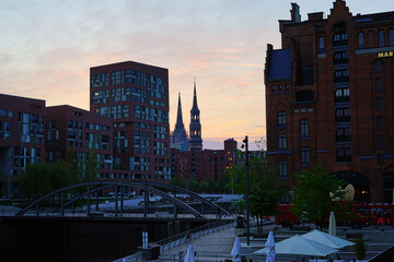 a canal of Historic Speicherstadt houses and bridges at evening with amaising skyview over warehouses famous place on Elbe river.