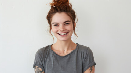 A cheerful woman with red hair tied in a bun, laughing joyfully in a casual grey t-shirt, her freckles and bright expression conveying happiness.