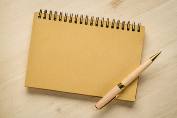 blank spiral notebook with a luxury pen against wooden background