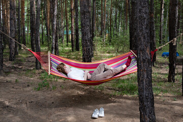 Obraz na płótnie Canvas Beautiful young woman relaxing in hammock in forest. Summer scenery, a beautiful morning in the bosom of nature. The girl admires the views and nature. Breathed fresh air. Beautiful morning light.