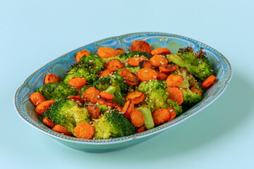 Asian-style stir-fried broccoli with carrot. Empty blue background.