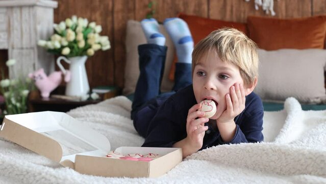 Beautiful blond child, boy, holding box with sweet macaroons for valentin