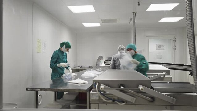Industrial Medical Production Facility. Multiple workers are operating on the medical production line. A worker is Placing the plastic packaging on the medical production conveyor line. Medicine.