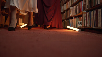 Women are mysteriously walking in library. Stock footage. Secret sorority in night library. Elegant...